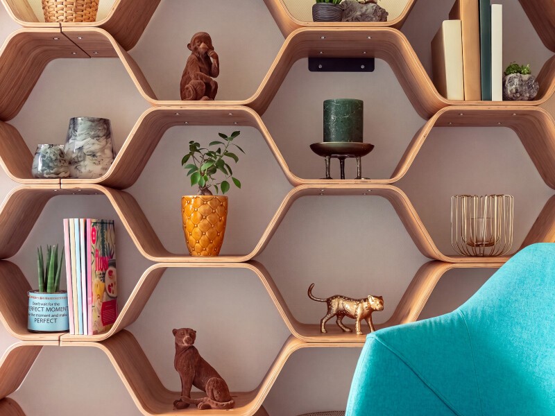 Intérieur des bureaux de Takaneo : étagères hexagonales en bois garnies de plantes, livres et objets décoratifs